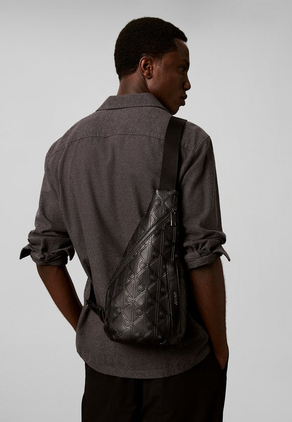 Calvin Klein CALVIN KLEIN DEBOSSED ALLOVER EMBLEM LOGO SLING BAG - Rucksack - black